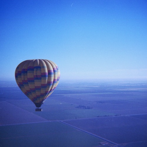 A Hot Air Balloon hovers over a blue landscape.